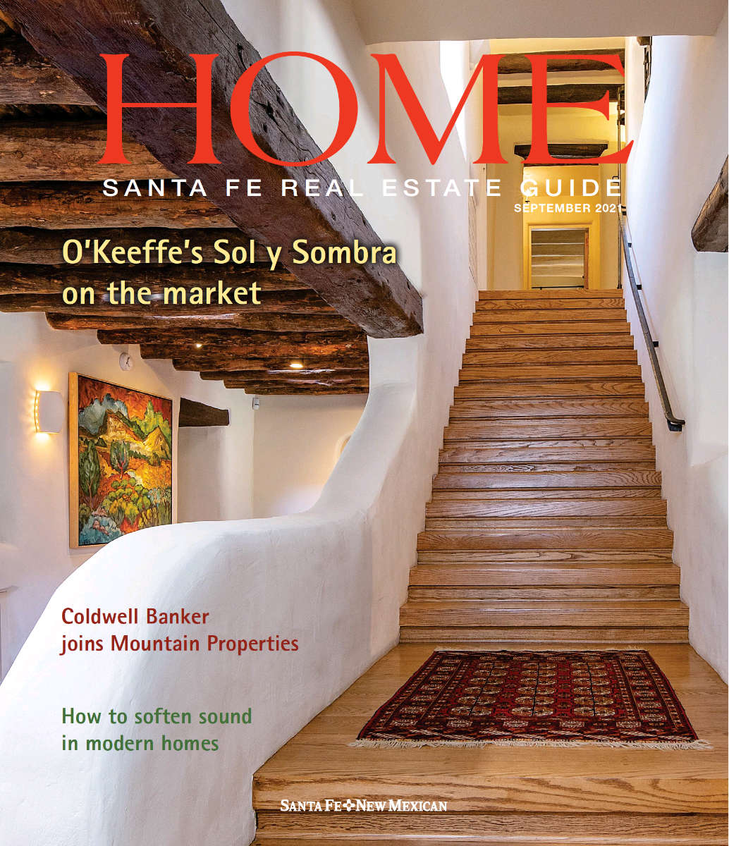 Santa Fe Real Estate Guide cover featuring traditional adobe architecture, wooden beams, and a staircase, highlighting architectural design in Santa Fe.