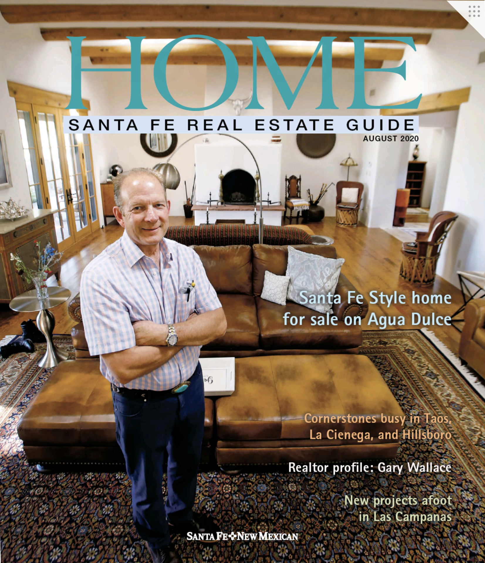 Man standing in a spacious Santa Fe style living room featured in the "HOME" real estate guide, showcasing traditional decor and architecture.